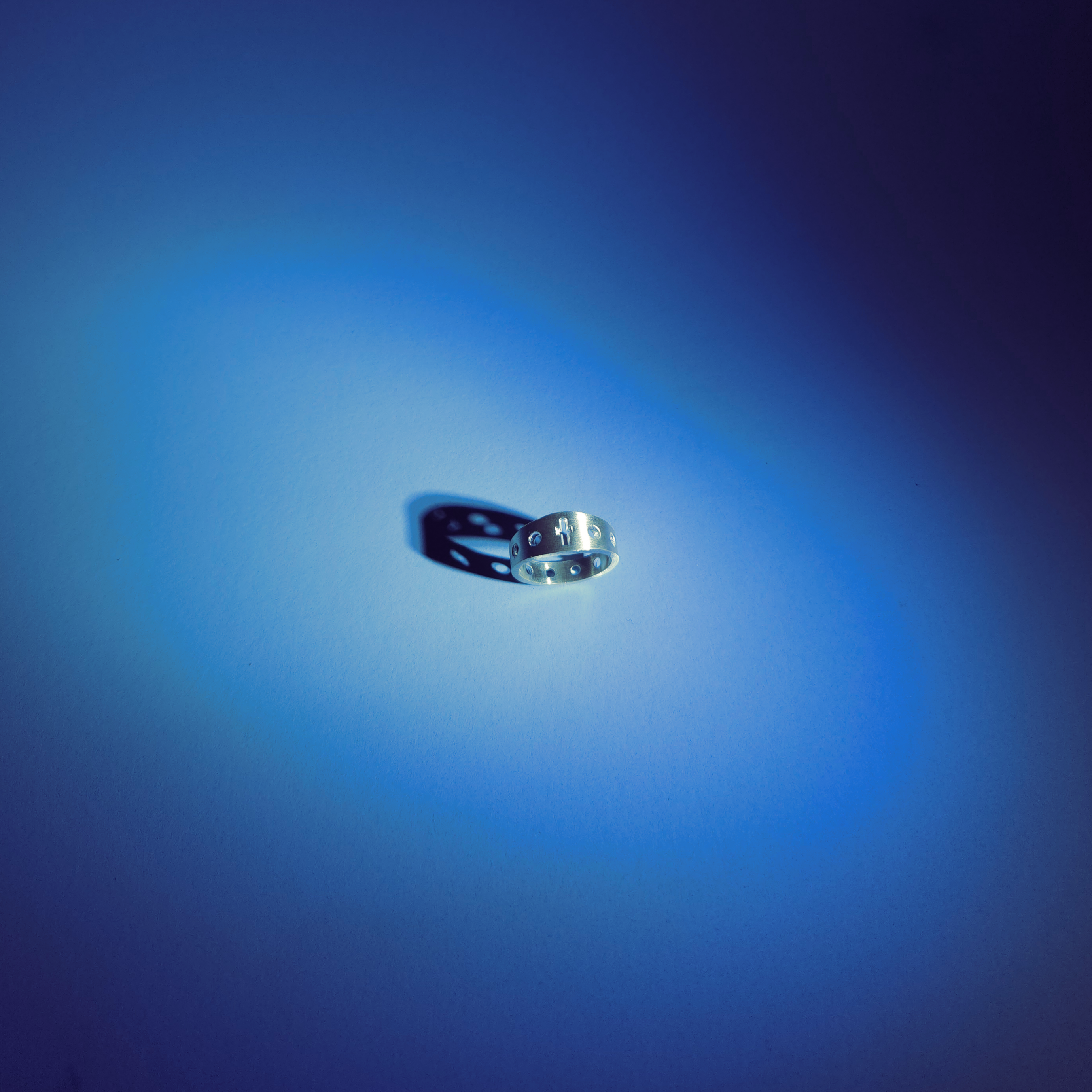 Silver rosary ring on a blue background