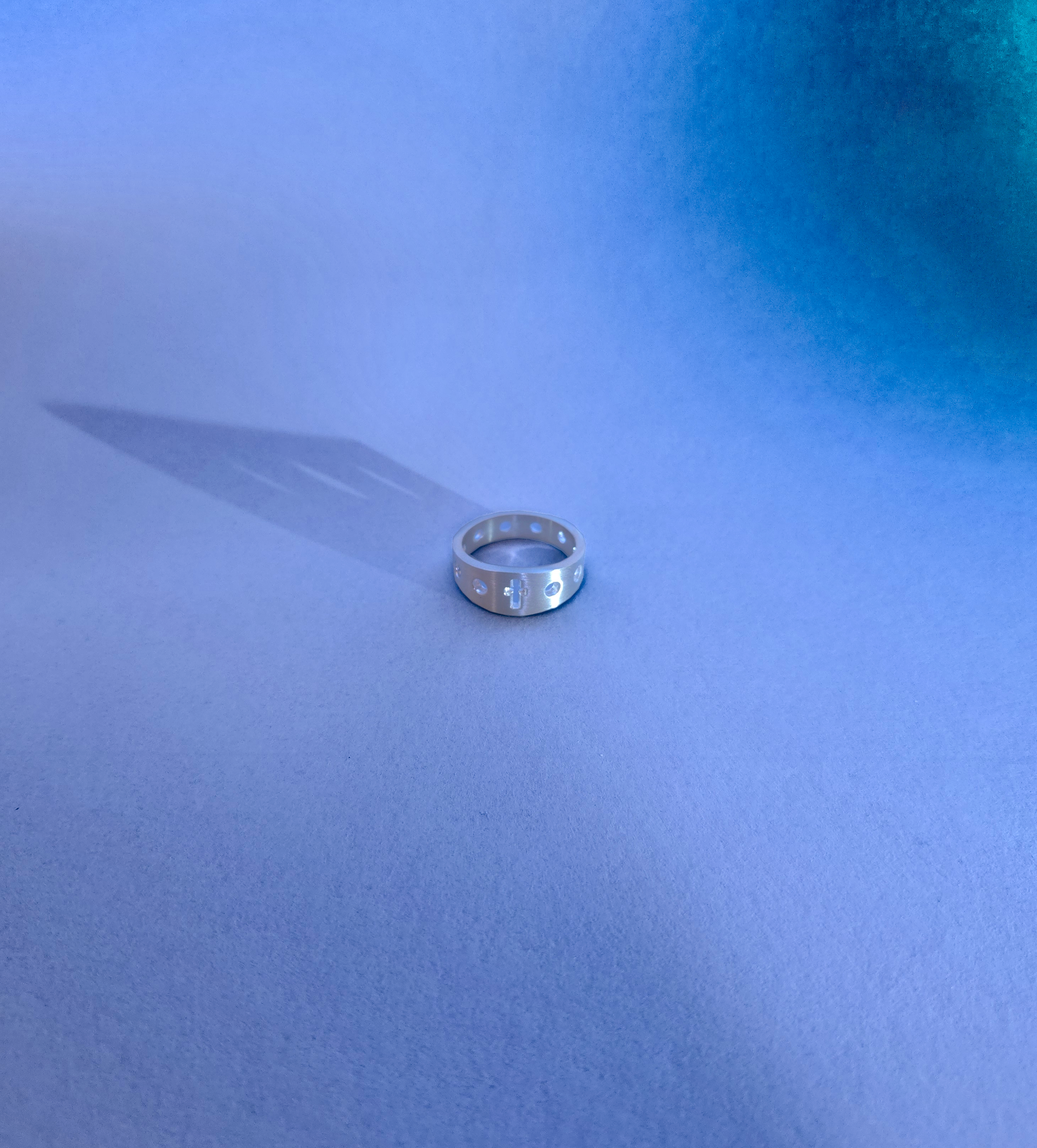 silver rosary ring on a baby blue backdrop
